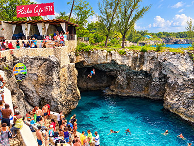 Cliff divers and swimmers at Rick’s Cafe in Negril, Jamaica, surrounded by limestone cliffs and turquoise Caribbean water.